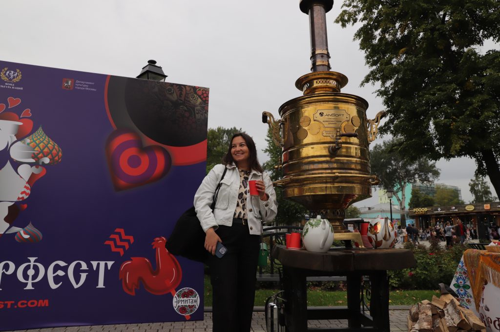 Гостья фестиваля Юлия Михайлова угощается иван-чаем, наливая кипяток из 100-литрового самовара