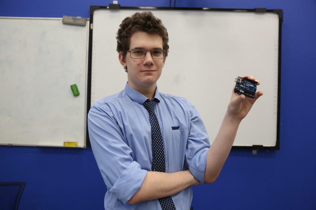 Студент МАИ Матвей Пятыго показывает модуль, что используется в качестве управляющего процессора в макете ровера